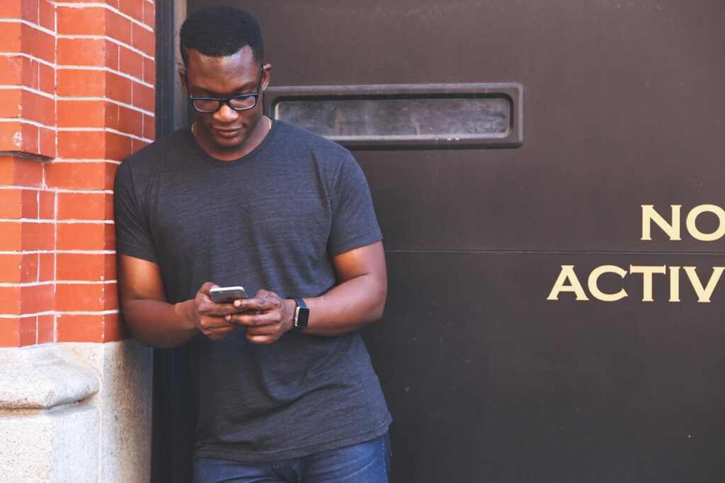 Man leaning against a wall absorbed by his smartphone, an image of the empathy crisis